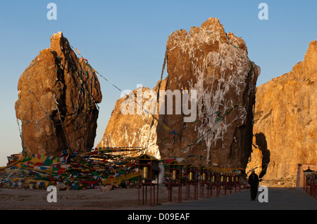 Pèlerin solitaire marche dernières rangées de roues de prière comme soleil levant, Sangrgompa Monastère, Lac Namtso, Tibet, Chine Banque D'Images