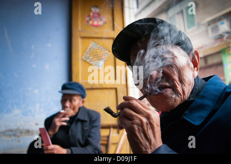 L'homme fume pipe tout en jouant aux cartes avec des amis le jour du marché dans le village à la périphérie de Chengdu, province du Sichuan, Chine Banque D'Images