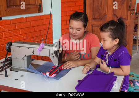 Une MÈRE ET SA FILLE DE BRODER AVEC UNE MACHINE À COUDRE, VILLAGE DE LA MINORITÉ LISU DANS LE NORD DE LA THAÏLANDE EN ASIE Banque D'Images