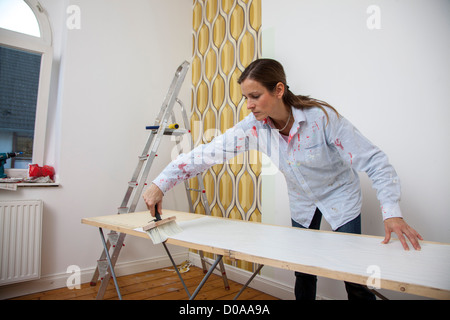 Jeune femme est en train de rénover sa maison. Paperhanging, nouveau fond d'écran. Faire vous-même. Banque D'Images