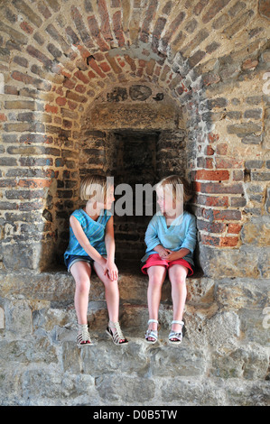 Les petites filles ASSIS DANS DES CRÉNEAUX DE NEVERS GATE ENTRÉE MONUMENTALE DE LA VILLE MÉDIÉVALE DE SAINT-VALERY-SUR-SOMME SOMME BAIE DE SOMME (80) FRANCE Banque D'Images