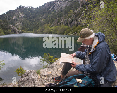 Randonnée dans la réserve naturelle de Cazorla Sierrra en Andalousie Espagne, male hiker resting par le lac, le déjeuner et l'étude de site Banque D'Images