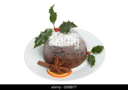 Le pudding de Noël décoré de houx et d'épices sur une plaque Banque D'Images