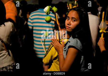 Jeune femme thaïlandaise prie w/ bougie, l'encens et des fleurs de lotus, Wat Saket, Phu Khao Thong (Montagne d'Or), Bangkok, Thaïlande. crédit : Kraig Lieb Banque D'Images