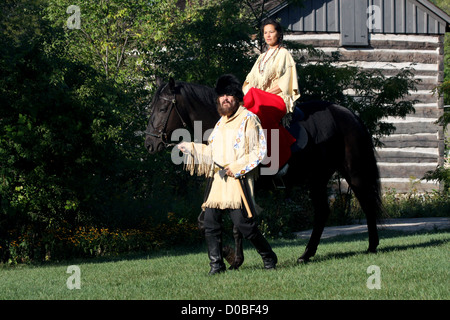 Un Native American Indian woman riding un cheval noir avec un pionnier Banque D'Images