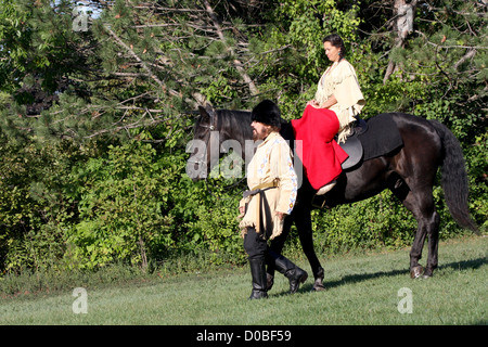 Un Native American Indian woman riding un cheval noir avec un pionnier Banque D'Images