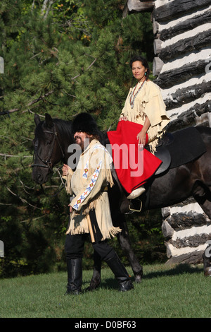 Un Native American Indian woman riding un cheval noir avec un pionnier Banque D'Images