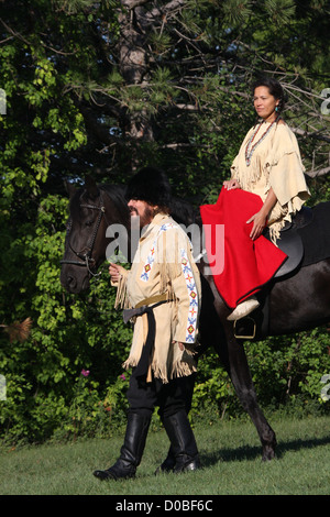 Un Native American Indian woman riding un cheval noir avec un pionnier Banque D'Images