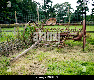 Un vieux râteau à cheval avec un siège, de la rouille dans un champ. Banque D'Images