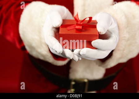 Photo de Père Noël les mains gantées tenant coffret rouge Banque D'Images