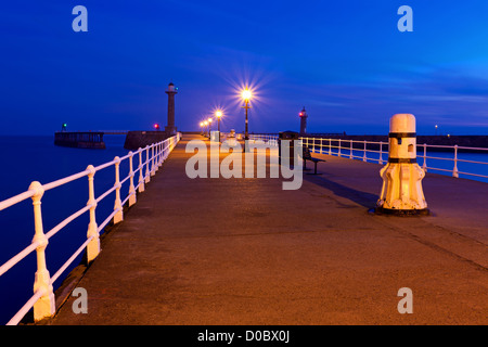 Le West Pier à Whitby, North Yorkshire illuminés par la lumière de l'lamposts Banque D'Images