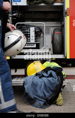 Re. Fireman de white watch à Pontypridd Fire Station en S Wales - casque de protection anti-incendie au manteau et gants sur le plancher Banque D'Images