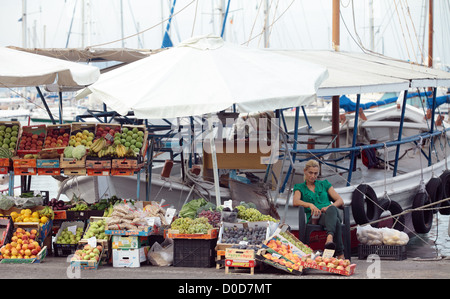 Un commerçant vend des fruits et légumes de son bateau sur le quai à Egine, ville sur l'île d'Égine, Banque D'Images