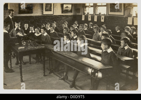 Carte postale originale des Edwardiens, des jeunes garçons et des enseignants dans une salle de classe, qui apprennent à peser, à peser et à mesurer, entre 1902 et 1906, au Royaume-Uni Banque D'Images