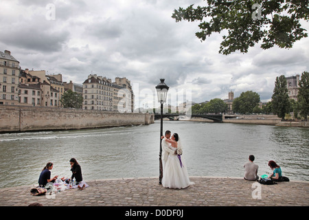 Mariée marié chinois POSANT POUR LEUR PHOTO DE MARIAGE AU MILIEU DE GENS PIQUE-NIQUE REPOSANT SUR LE POINT DE L'ILE SAINT-LOUIS PARIS (75) FRANCE Banque D'Images