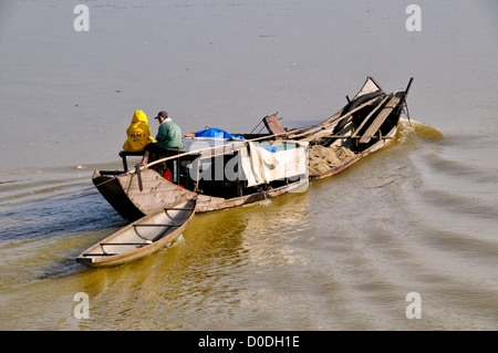 HUE, Vietnam — Un sampan en bois transportant du sol dragué remonte les eaux brunes de la rivière des parfums à Hue, Vietnam. Banque D'Images