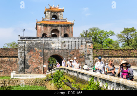 HUE, Vietnam — les touristes traversent un pont sur les douves depuis une tour de garde à la ville impériale de Hue, Vietnam. Palais clos et fortifié, le complexe comprend la Cité interdite pourpre, qui était le sanctuaire intérieur de la maison impériale, ainsi que des temples, des cours, des jardins et d'autres bâtiments. Une grande partie de la ville impériale a été endommagée ou détruite pendant la guerre du Vietnam. Il est maintenant classé au patrimoine mondial de l'UNESCO. Banque D'Images