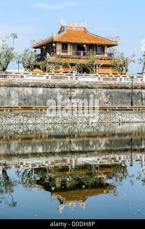 HUE, Vietnam — Un bâtiment de la ville impériale de Hue, Vietnam, se reflète sur l'eau des douves défensives. Palais clos et fortifié, le complexe comprend la Cité interdite pourpre, qui était le sanctuaire intérieur de la maison impériale, ainsi que des temples, des cours, des jardins et d'autres bâtiments. Une grande partie de la ville impériale a été endommagée ou détruite pendant la guerre du Vietnam. Il est maintenant classé au patrimoine mondial de l'UNESCO. Banque D'Images