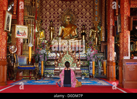 Jeune femme qui prie dans le temple Wat Phra Singha, Chiang Rai, Thaïlande, Asie Banque D'Images