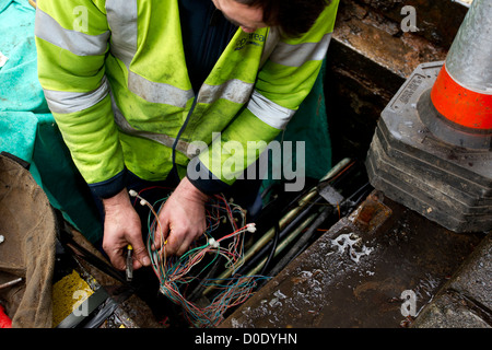 BT Openreach ingénieur téléphone téléphone mending connexion dans le trou de l'homme Banque D'Images