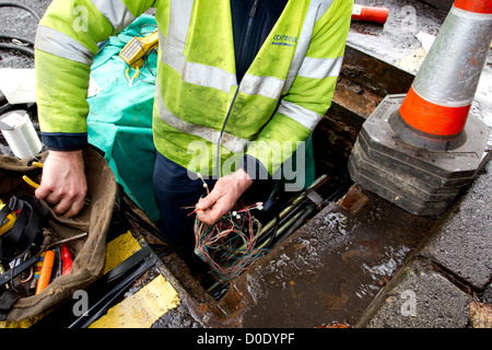 BT Openreach ingénieur téléphone téléphone mending connexion dans le trou de l'homme Banque D'Images