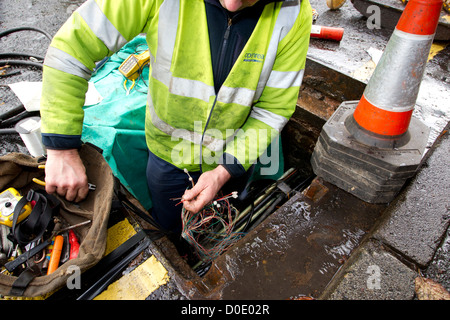 BT Openreach ingénieur téléphone téléphone mending connexion dans le trou de l'homme Banque D'Images