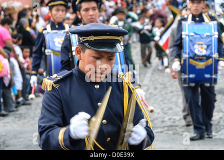 ANTIGUA GUATEMALA, Guatemala — dans la matinée de la veille de la fête de l’indépendance du Guatemala (célébrée le 15 septembre), des centaines d’écoliers d’Antigua et des villages environnants défilent dans un défilé de groupes scolaires à Antigua, certains en costume et d’autres en uniforme scolaire. Le défilé comprend également des orchestres de marche de l'école et des cheerleaders. Le cortège commence au Parque Central et passe devant l'église jaune vif de la Merced et sur le stade municipal. Banque D'Images