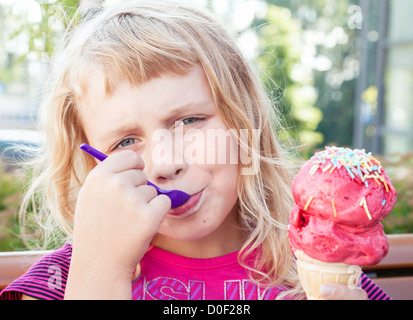 Petite fille mange gros fruit ice-cream in the park Banque D'Images