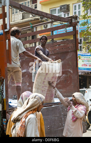 Décharger un camion de travailleurs avec des sacs de ciment à Mumbai, Inde Banque D'Images