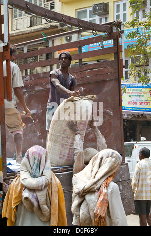 Décharger un camion de travailleurs avec des sacs de ciment à Mumbai, Inde Banque D'Images