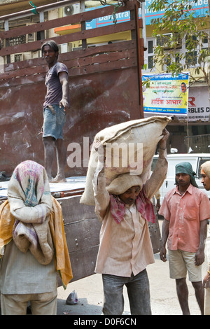 Décharger un camion de travailleurs avec des sacs de ciment à Mumbai, Inde Banque D'Images