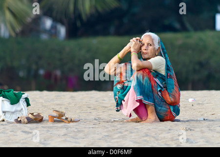 Femme assise dans le sable sur la plage de Chowpatty à Mumbai, Inde Banque D'Images