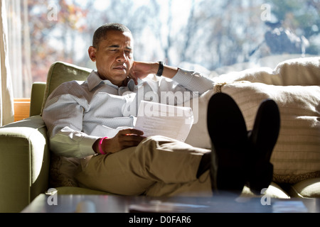 Le président américain Barack Obama se lit des documents tout en répondant avec les conseillers le 21 octobre 2012 à l'intérieur de sa cabine à Camp David. Banque D'Images