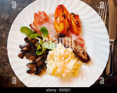 Un petit-déjeuner anglais complet traditionnel d'oeufs brouillés au bacon et champignons châtaigne saucisses tomates frits servi au Yorkshire Banque D'Images