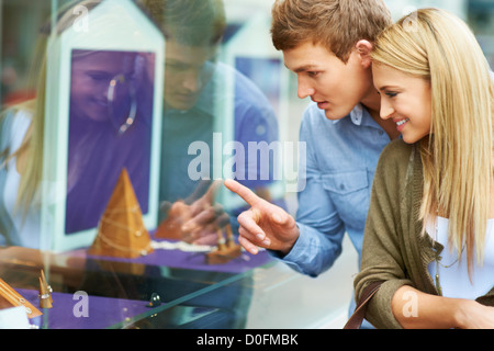 Jeune couple à la recherche d'un affichage de bijoux à travers une vitrine Banque D'Images