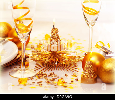 Photo de Noël romantique dîner, deux verres de champagne garni de ruban doré, belle petite bougie Banque D'Images