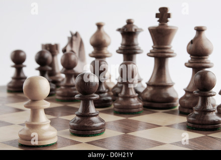 Le pion blanc noir face à pièces d'échecs sur un échiquier Banque D'Images