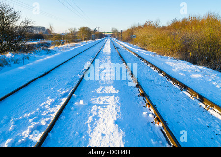 Les voies de chemin de fer se déplace en ligne droite à travers la campagne après l'hiver la neige, Lancashire, England, UK Banque D'Images