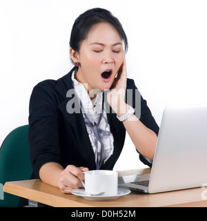 Jeune femme d'affaires de bâiller à son bureau avec une tasse de café, c'est modèle femme asiatique. Banque D'Images