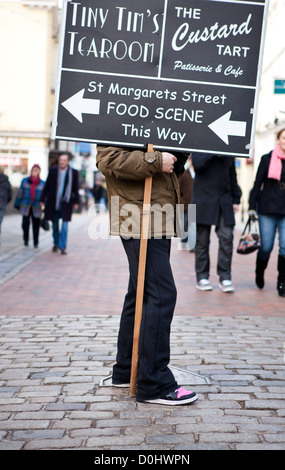 Un homme se tenait dans la rue principale holding a placard avec les instructions de magasins locaux. Banque D'Images