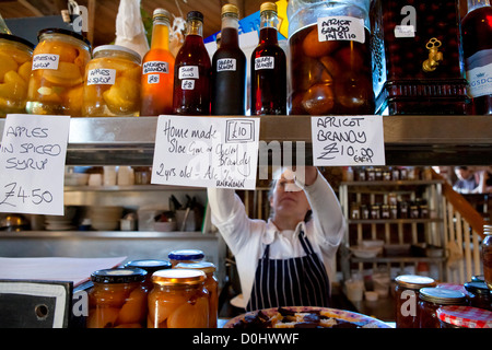 Un commerçant du marché alimentaire place sur l'affichage à son étal dans le hangar de marchandises à Canterbury. Banque D'Images