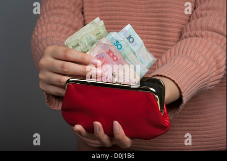 Chinese woman holding Yuan billets de la monnaie officielle de la Chine continentale avec un sac à main rouge Banque D'Images