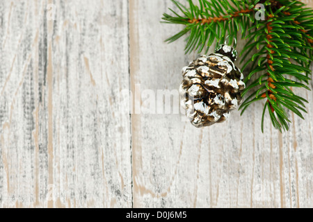 Or de Noël cône de pin on tree branch avec fond de bois Banque D'Images