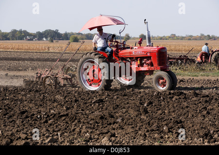 Modèle Farmall M labourer un champ dans une ferme près d'Hébron, l'Illinois lors d'une démonstration de labour tracteur antique. Banque D'Images