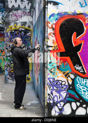 La pulvérisation à l'homme de l'écriture graffiti-land sur la rive sud de Londres. Banque D'Images