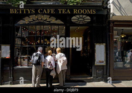 Les personnes à la recherche de la fenêtre de peu de Bettys cafe et salons de thé dans la région de Stonegate. Banque D'Images