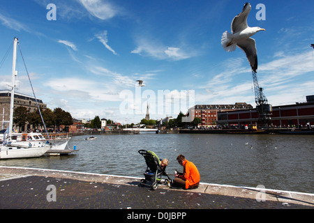 Un père et son fils s'asseoir à côté de la rivière Avon à Harbourside de Bristol. Banque D'Images