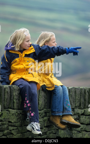 UK, Yorkshire, Peak District, deux jeunes filles assis sur le mur de pierre. Banque D'Images