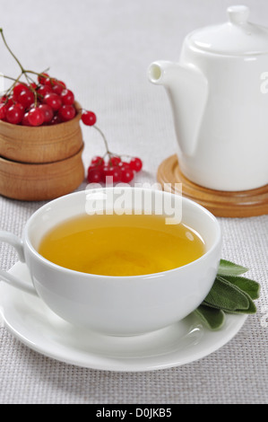 Thé de sauge de fines herbes en blanc tasse avec viburnum dans bol en bois Banque D'Images