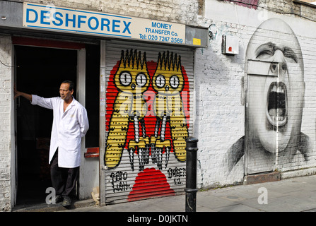 Un homme à la recherche vers l'entrée de Brick Lane Rue Hanbury street avec l'art. Banque D'Images